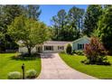 Inviting single-story home featuring a lush front lawn, mature trees, and a concrete driveway leading to the entrance at 340 Monivea Ln, Roswell, GA 30075