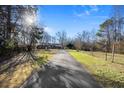 Long driveway leading to a brick home, bordered by a spacious, tree-lined yard on a sunny day at 7427 Hollis Rd, Douglasville, GA 30135