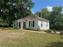 Quaint white home with black shutters is surrounded by mature trees and a well-manicured lawn at 95 Whitlock Sw Ave, Marietta, GA 30064