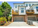 Rear view of a modern townhouse with a wooden balcony, brick foundation, and a convenient two-car garage at 219 Phillips Ln, Alpharetta, GA 30009
