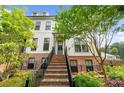 Inviting two-story townhome boasts classic architectural design with brick accents, an inviting staircase, and lush landscaping at 219 Phillips Ln, Alpharetta, GA 30009