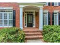 Elegant entrance with a black front door, white columns, and brick steps at 5010 Bonnie Way, Roswell, GA 30075