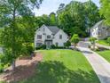 A house with a sprawling lawn and driveway, set against a backdrop of lush green trees at 103 Caracas Dr, Woodstock, GA 30188