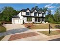 Beautiful two-story home with black trim, white siding, well-manicured lawn, and three-car garage at 320 Dodd Ln, Alpharetta, GA 30005