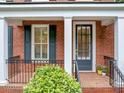 Close up of charming front porch featuring brick, white columns, and black railings and shutters at 5000 Davenport Pl, Roswell, GA 30075