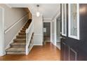 Inviting foyer featuring wood floors, a staircase with white banister, and a decorative pendant light at 745 Greenvine Pl, Roswell, GA 30076