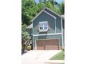 Charming home featuring green siding, a brown garage door, and a window box filled with flowers at 313 India Ln, Canton, GA 30114