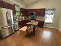 The open kitchen offers stainless steel appliances, a large island, and burgundy cabinets at 313 India Ln, Canton, GA 30114