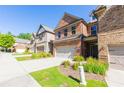 Brick townhome with a two-car garage and neatly landscaped front yard in a suburban neighborhood at 9872 Cameron Parc Cir, Johns Creek, GA 30022