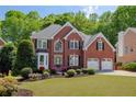 Stately brick home shows off a lush lawn, mature trees, and a practical two-car garage at 1105 Anemone Nw Way, Acworth, GA 30102