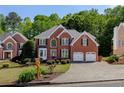Attractive brick home displays a well-kept lawn, mature trees, and a convenient two-car garage at 1105 Anemone Nw Way, Acworth, GA 30102