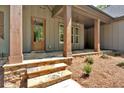 Inviting front porch with stone steps, wooden pillars, and a stained wood front door at 33 Cedar Gate Ln, Kingston, GA 30145