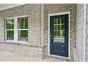Close-up of the front door with glass paneling, complemented by the surrounding gray brick facade and trim at 3970 Brushy St, Powder Springs, GA 30127