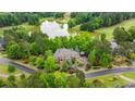 Beautiful stone house with a brick driveway surrounded by trees, landscaping, golf course and a pond in the backyard at 939 Middle Fork Trl, Suwanee, GA 30024