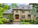Elegant brick home featuring a stone archway, a wooden double door entry, and a perfectly manicured landscape at 939 Middle Fork Trl, Suwanee, GA 30024