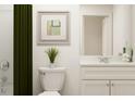 Contemporary bathroom featuring a green shower curtain, toilet, white vanity, and artwork at 2489 Cotton Ln, Douglasville, GA 30135