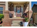 Inviting front porch with brick columns, decorative wreath on the door, and potted plants adding a welcoming touch at 7933 Heathmore Dr, Fairburn, GA 30213