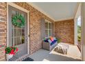 Inviting front porch with brick facade, outdoor seating, and a decorative wreath on the front door at 1074 Nash Springs Cir, Lilburn, GA 30047
