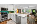 A kitchen with stainless steel appliances, white cabinets and countertops, and an emerald backsplash, open to the living room at 1635 Briarcliff Rd # 8, Atlanta, GA 30306