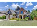Attractive two-story home with a well-maintained lawn, mature landscaping, and double garage at 1563 Country Wood Dr, Hoschton, GA 30548