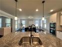 Kitchen with granite countertop, double sink, pendant lights, and a view into the dining area and living room at 2506 Monta Vista Way, Hoschton, GA 30548