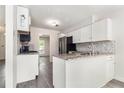 Updated kitchen features white cabinets, stone countertops, mosaic backsplash, and stainless steel appliances at 520 Cranberry Pl, Roswell, GA 30076