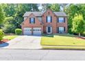 A two-story brick home with a well-manicured lawn, mature trees, and a two-car garage at 1500 Highland Farm Dr, Suwanee, GA 30024
