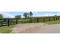 Black wooden fence and gated entrance with a horse barn in the background at 200 Mcclure Dr, Cumming, GA 30028