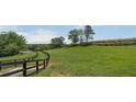 Scenic grassy field with mature trees and wooden fencing at 200 Mcclure Dr, Cumming, GA 30028