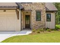 Charming front entrance with stone accents, a wooden door, and a well-maintained lawn at 208 Regester Way, Peachtree City, GA 30269