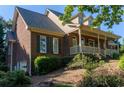 Brick home featuring a side entry garage, well-maintained landscaping, and a covered front porch at 1210 Lancelot Ct, Loganville, GA 30052