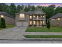 Charming two-story brick home featuring a double-door garage and welcoming front porch and upstairs balcony at dusk at 412 Live Oak Pass, Loganville, GA 30052
