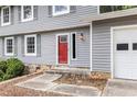 Close up of the home's entryway, featuring a bright red door, stone accents, and gray siding at 1023 Chartley Sw Dr, Lilburn, GA 30047