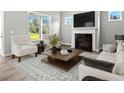 Cozy living room boasts a fireplace, large windows with backyard views, and stylish furniture at 1101 Cooks Farm Way, Woodstock, GA 30189