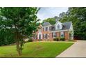 Traditional brick home with lush green lawn and mature trees creating a picturesque suburban setting at 1200 Larson Sw Ln, Marietta, GA 30064
