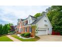 Rear view of a brick home showcasing a well-maintained lawn, attached garage, and manicured landscaping at 1200 Larson Sw Ln, Marietta, GA 30064