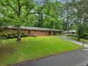 Lush greenery surrounds this brick home with a carport and well-manicured lawn at 1728 N Holly Ne Ln, Atlanta, GA 30329