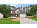 Inviting two-story home featuring a front porch, red shutters, an attached garage, and a well-maintained lawn at 3055 Kennesaw Nw Dr, Kennesaw, GA 30152