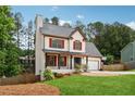 Well-maintained two-story home with an inviting front porch, red shutters, manicured lawn, and attached garage at 3055 Kennesaw Nw Dr, Kennesaw, GA 30152