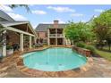 Backyard pool area featuring stone patio, waterfall feature and covered patio area at 18 Starlight Dr, Cartersville, GA 30121
