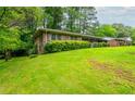 A charming single-story brick house on a green, gently sloping lawn, surrounded by lush trees at 3549 Dogwood Dr, Powder Springs, GA 30127