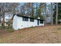 Side view of a white painted brick home with black window trim, providing a glimpse of the backyard at 3215 Pennignton Cir, Atlanta, GA 30354