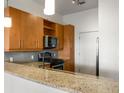 Granite counters and stainless steel appliances complement the wood cabinets in the well-appointed kitchen at 870 Inman Village Pkwy # 203, Atlanta, GA 30307