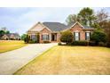 Inviting brick home features manicured landscaping, classic design elements, and a spacious front lawn at 118 Jasmine Way, Carrollton, GA 30180