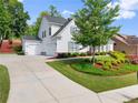 Side view of a two-story home with a three car garage and manicured lawn at 5875 Windjammer Pt, Cumming, GA 30041