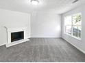 Bright living room featuring a cozy fireplace, large window for natural light, and neutral gray carpet at 7007 Setters Way, Lithonia, GA 30038