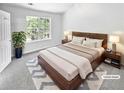 Comfortable main bedroom featuring neutral carpet, an inviting bed, and a leafy view from the window at 7007 Setters Way, Lithonia, GA 30038