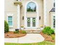 Close-up of the front entrance features a stone walkway, double doors with floral wreaths, and stylish exterior lighting at 10490 Cranchester Way, Alpharetta, GA 30022