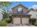 Exterior shot of a home with a brick front, a two-car garage, and lush landscaping at 6664 Saint Jude Dr, Fairburn, GA 30213