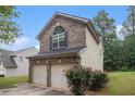 View of the home's exterior featuring a two-car garage and attractive brick accents at 6664 Saint Jude Dr, Fairburn, GA 30213